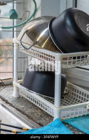 Kitchen drying rack with pots near sunny window Stock Photo