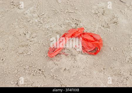 Red plastic bag on sandy beach Stock Photo
