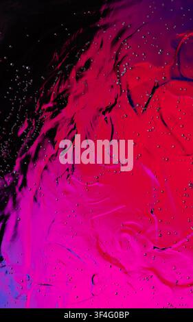 Abstract magenta and red liquid creating a dynamic swirling pattern with small bubbles Stock Photo
