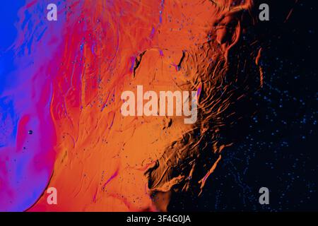 Abstract colorful liquid texture with orange, blue, and black areas and tiny spreading droplets Stock Photo