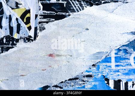 Textured surface with layers of old torn paper posters and paint. Blue, black, and white colors placard pieces on wall Stock Photo