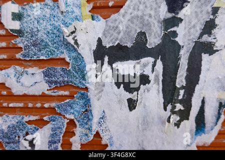 Close-up of weathered wall with peeling old advertising posters in shades of blue and white. Abstract urban background Stock Photo