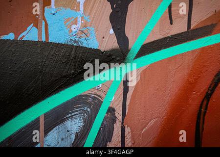 Old grunge wall with orange, black, green, blue color paint strokes. Abstract urban wall background outdoors Stock Photo