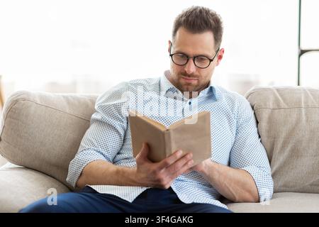 Handsome man reading a book at home Stock Photo