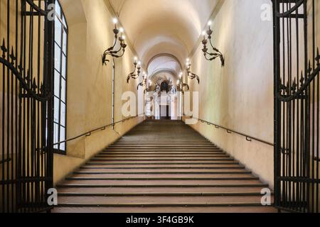 Bologna, Italy - May 2026: Grand monumental staircase with vaulted ceiling and wrought iron sconces inside Palazzo d'Accursio Stock Photo