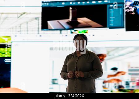 Happy woman uses digital videowall to look at personalized video recommendations delivered instantly. Jolly VOD platform user enjoying unlimited streaming opportunities in digital era Stock Photo
