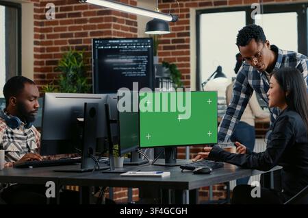 Developers analyze source code with green screen while colleagues work on algorithms and a chroma key mockup supports replaceable software screen use. Stock Photo