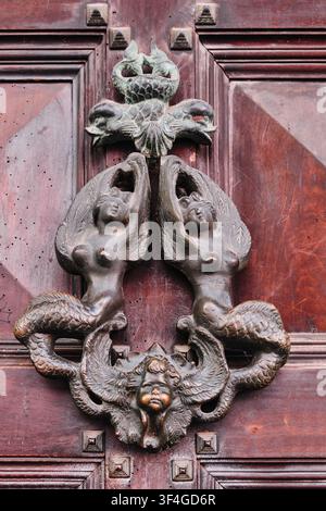 Bologna, Italy - May 2026: Close up view of an ornate antique bronze door knocker with mermaid figures Stock Photo