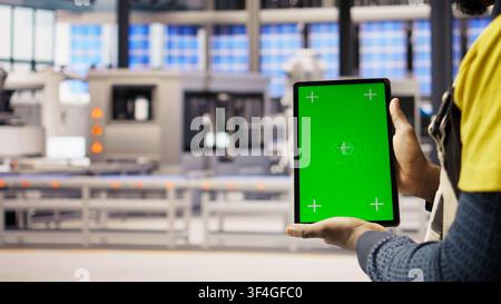 Photovoltaics plant worker uses chroma key notebook to follow maintenance procedures. Solar panels factory engineer analyzes performance data with isolated screen laptop, camera A close up Stock Photo