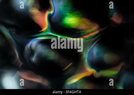 Abstract flowing forms in green, blue, orange and yellow glow against a black background, creating a fluid composition of sweeping curves, soft light Stock Photo