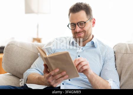 Handsome man in glasses reading a book at home Stock Photo