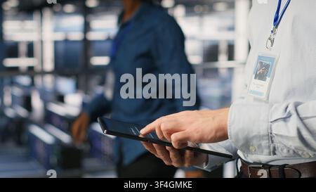 Close up of data center software developer doing maintenance tasks on tablet, ensuring optimal performance. Worker reviewing diagnostics and applying patches to server hub equipment Stock Photo