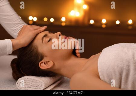 Sleeping woman getting healing face massage at spa Stock Photo