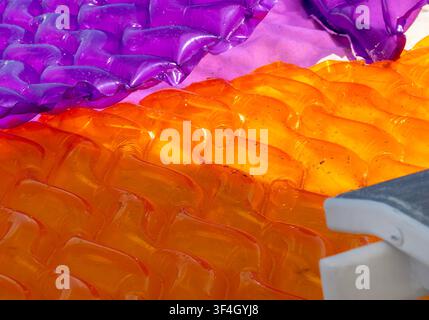 Brightly colored inflatable rafts in purple and orange beside a beach chair Stock Photo