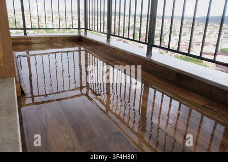 Water pooled on wooden floor in balcony area Stock Photo
