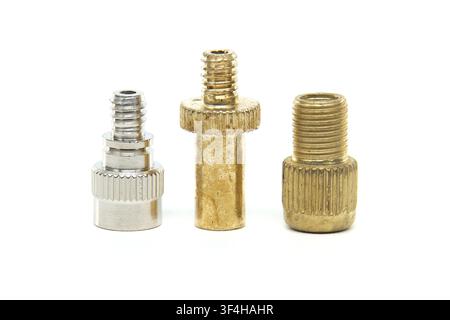 Three metal valve adapters, one silver and two brass, are displayed against a white background for easy comparison and selection Stock Photo