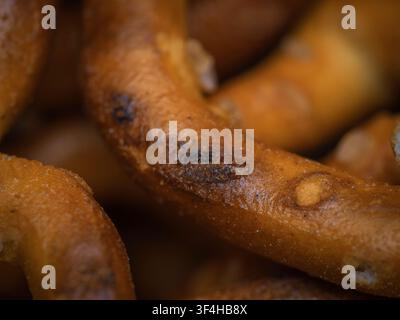 Macro close up shot of a crunchy salted baked pretzel surface with golden brown texture and salt grains Stock Photo