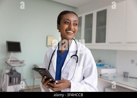 Happy young African American doctor woman using mobile phone Stock Photo