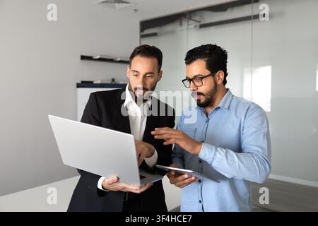 Multiethnic business colleagues working on digital project using laptop Stock Photo