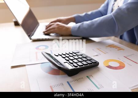 Accountant working on laptop at desk with calculator and report Stock Photo