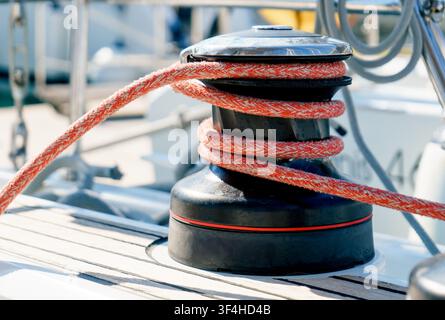 Close-up of a sailing winch with braided rope secured on a yacht deck in a marina. Concept of seamanship, navigation, teamwork, technology, adventure Stock Photo