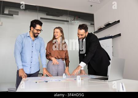 Smiling multiethnic business team reviewing charts in corporate office Stock Photo