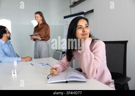 Female thinking on ideas, writing notes in notebook during meeting Stock Photo