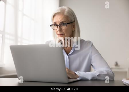 Worried senior female feel nervous stressed looking on laptop screen Stock Photo