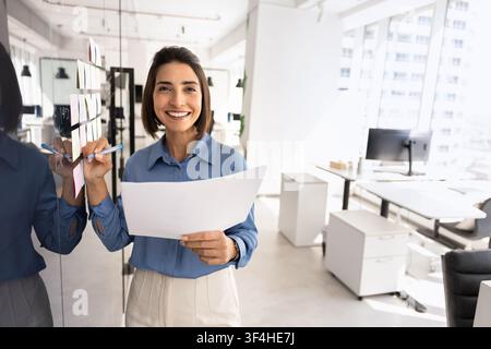 Businesswoman stands next to board covered with sticky notes Stock Photo