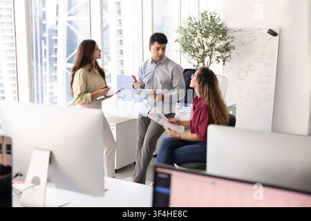 Diverse colleagues engaging in teamwork, collaborating on project in office Stock Photo
