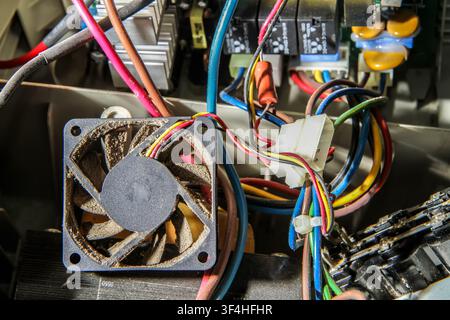 Disassembled computer power supply unit. Dusty cooling fan close-up. Maintenance of computer equipment. Stock Photo