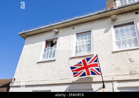 Traditional whitewashed building in Yarmouth on the Isle of Wight displaying a Union Jack flag beneath sash windows against a clear blue summer sky hi Stock Photo