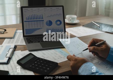 man review financial spreadsheets on laptop dashboard, calculator,, financial document checking figures with pen to support document verification, rep Stock Photo