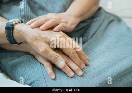 Close up elderly affectionate woman covering wrinkled hands of mature husband, showing love and support at home. Caring middle aged family couple enjo Stock Photo