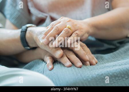 Close up of senior couple holding hands for bonding support and marriage together. Selective focus of man and woman holding hands of each other. Stock Photo