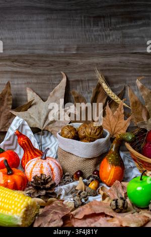 Autumnal arrangement showcasing various pumpkins, gourds, dried leaves, and nuts on a rustic wooden background Stock Photo