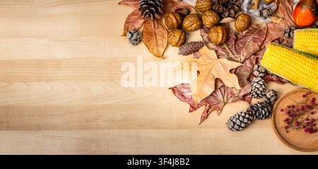 Autumnal background showcasing dried leaves, corn cobs, walnuts, and pinecones on a wood surface Stock Photo
