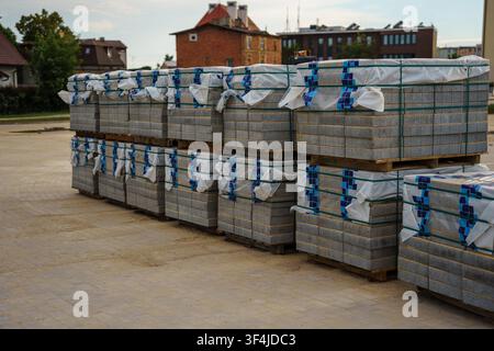Stacked gray paving stone blocks on wooden pallets, ready for construction, landscaping projects, construction industry supply, landscaping inventory Stock Photo