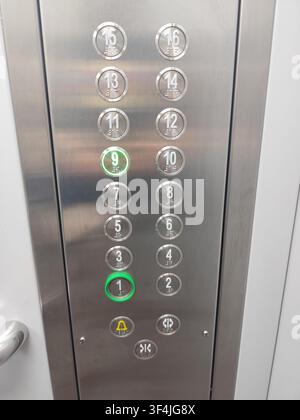Elevator Control Panel with Illuminated Round Floor 16 Buttons in a Modern Building Metal Interior Panel. Green light on nine Stock Photo