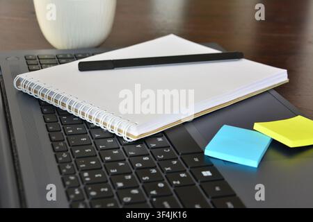 Notebook and Pen on Laptop Keyboard with Sticky Notes front view Stock Photo