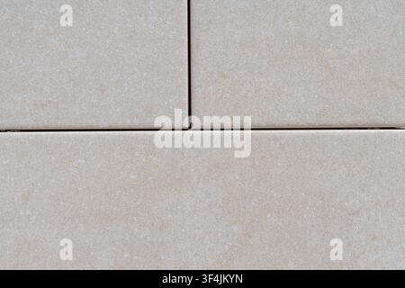 A detailed view of neutral-colored rectangular tiles, showcasing their speckled surface and the thin dark lines between them Stock Photo