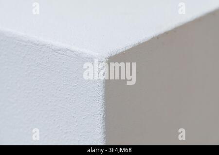 A detailed macro shot focuses on the rough texture and sharp edge of a white surface, highlighting subtle shadows and light play Stock Photo