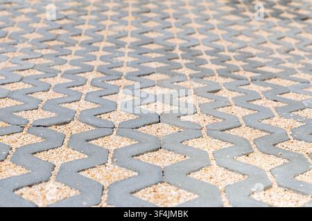 A close-up view of a modern permeable paving system featuring interlocking concrete blocks filled with fine gravel for drainage and aesthetics Stock Photo