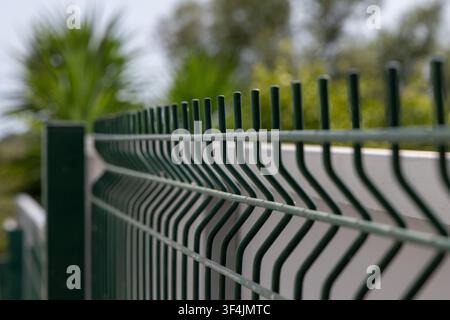 A close-up view of a dark green wire mesh fence with a shallow depth of field, highlighting its repeating pattern and texture Stock Photo