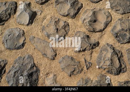 Top view of dark stone pavement in sand, abstract cobble and basalt texture background with copy space Stock Photo