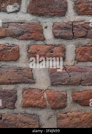 Vertical close-up of old rustic red brick wall texture with rough grey mortar joints and copy space Stock Photo