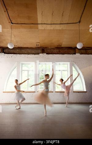 Ballet dancers rehearsing energetic group sequence in sunlit studio Stock Photo