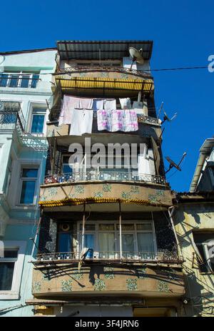 A narrow weathered apartment building in the Bulbul district of Beyoglu, Istanbul, Turkiye. Projecting concrete balconies are covered with brown tiles Stock Photo