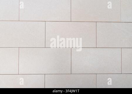 A close-up view of a textured wall constructed from rectangular, light beige stone blocks with subtle variations in tone and fine grain Stock Photo