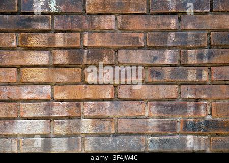 Red brick and mortar texture. Weathered, multicolored brick wall composed of rectangular clay bricks in shades of earthy brown. Stock Photo